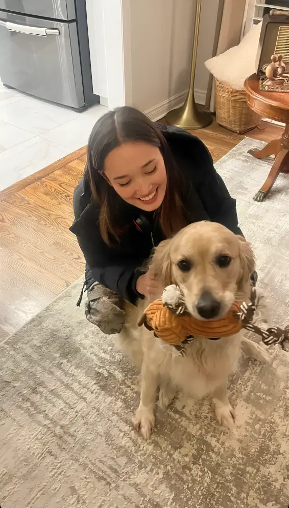 Samantha kneeling beside a happy dog while offering a treat